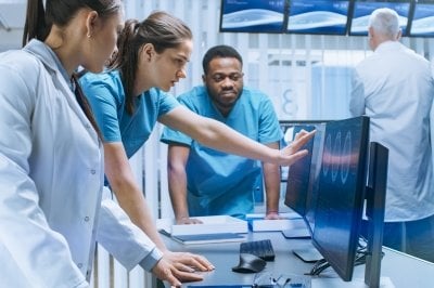 Doctors and nurses view data and images on a computer.