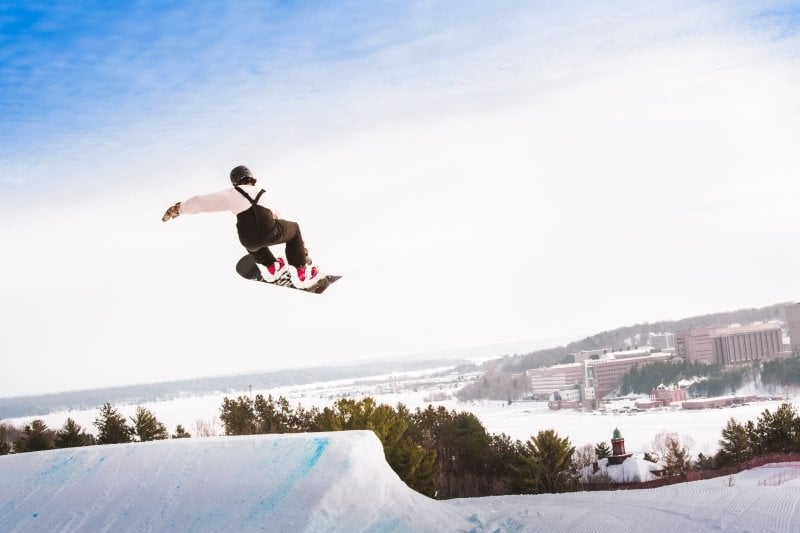 Snowboarder in the air after a jump with the campus in the background.