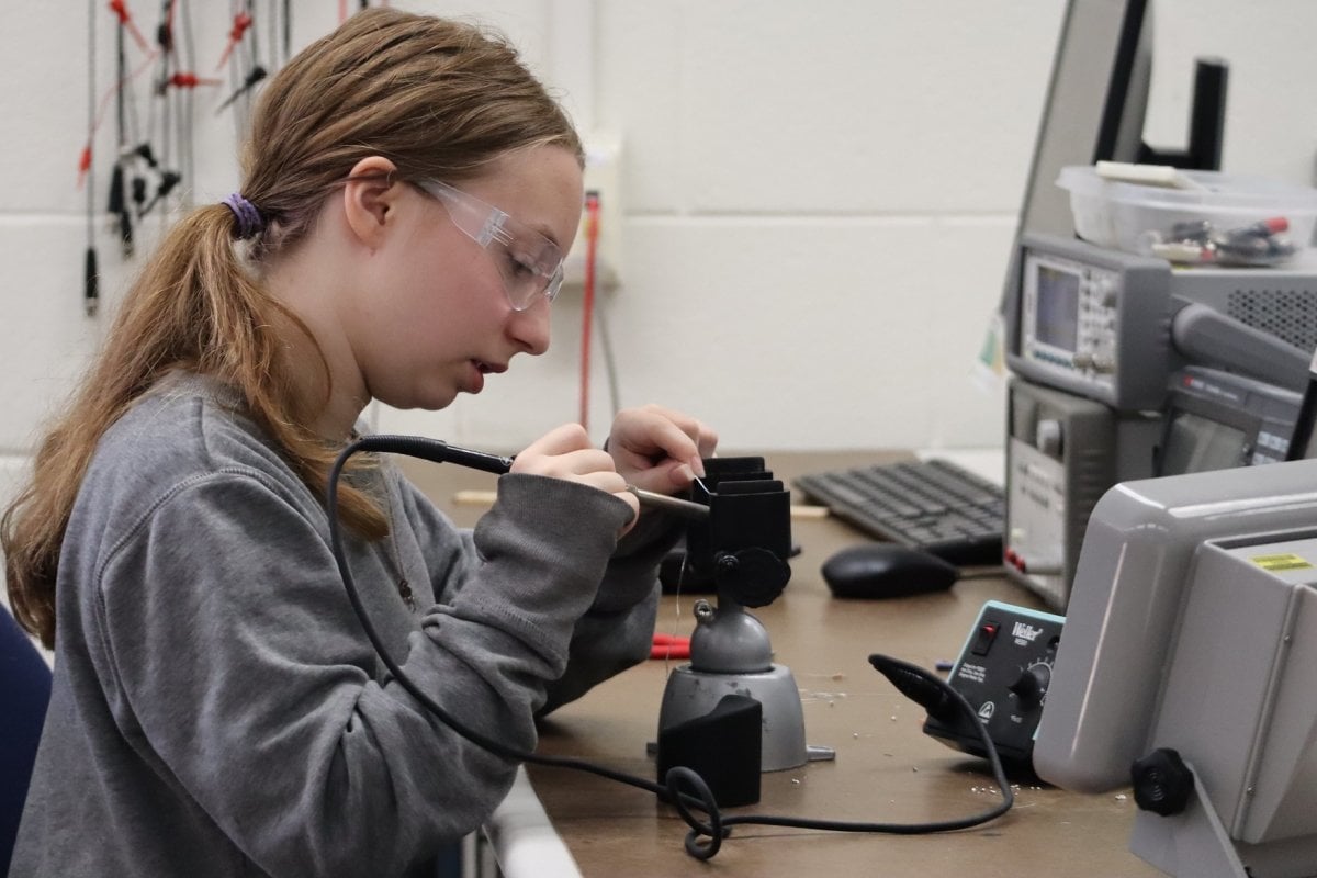 SYP Student working at a bench, soldering.