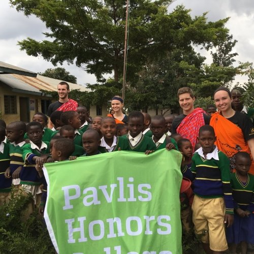Students on an immersion trip holding a PHC Banner