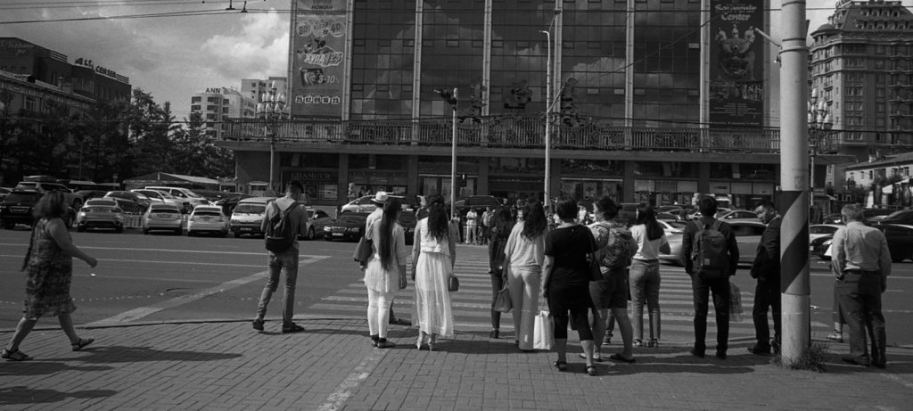 A black and white photo of a crowd looking at a large building, their backs to the camera