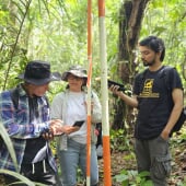 three people working on fieldwork in the forest