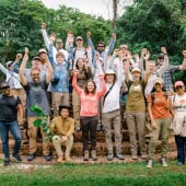 group of students and faculty on the study away trip to surinmae standing in a group with arms raised in joy