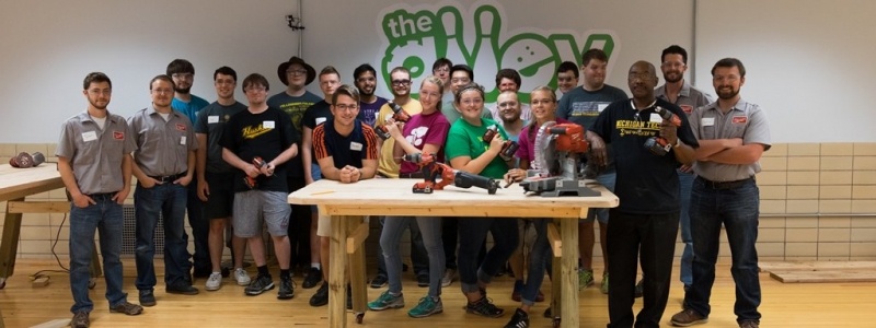 Group photo of students in the makerspace with a work table in front of them.