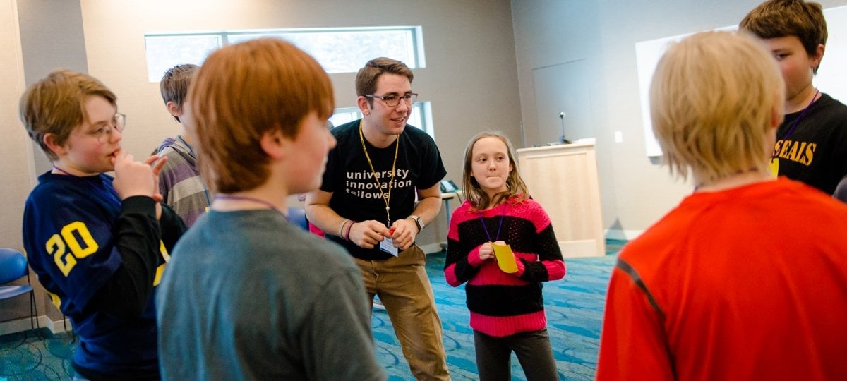 A college student teaching a group of elementary school students