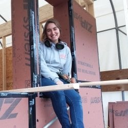 A woman sits on the framework of a building in progress