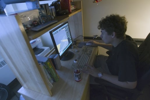 Student in his room, working on his computer.
