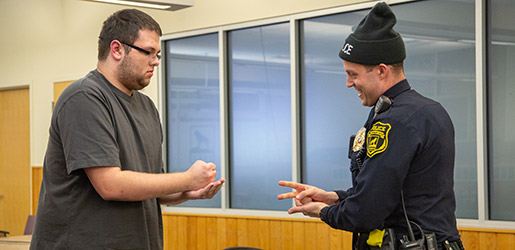 Public safety officer playing rock paper scissors with a student