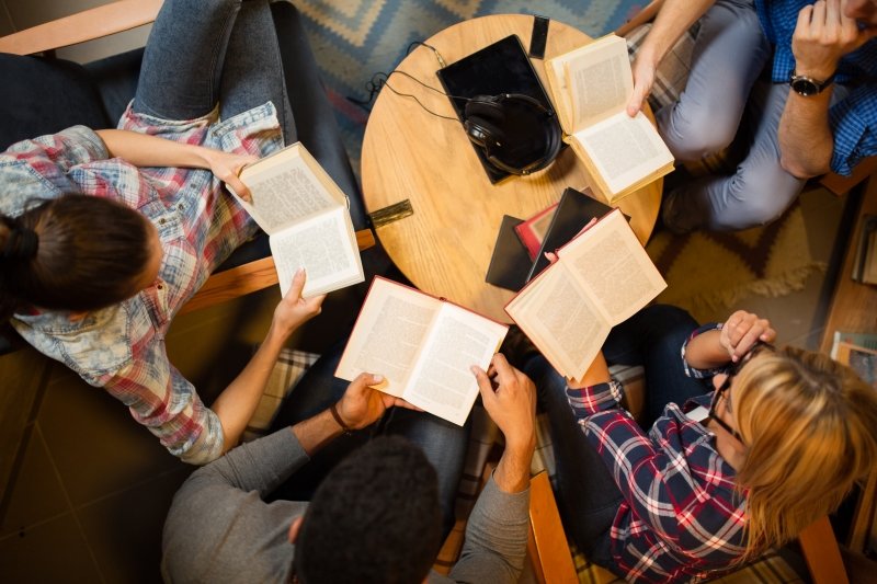 Group of people sitting with novels in a circle