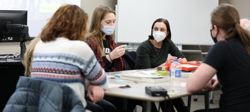 Image of four Humanities students collaborating around a table talking