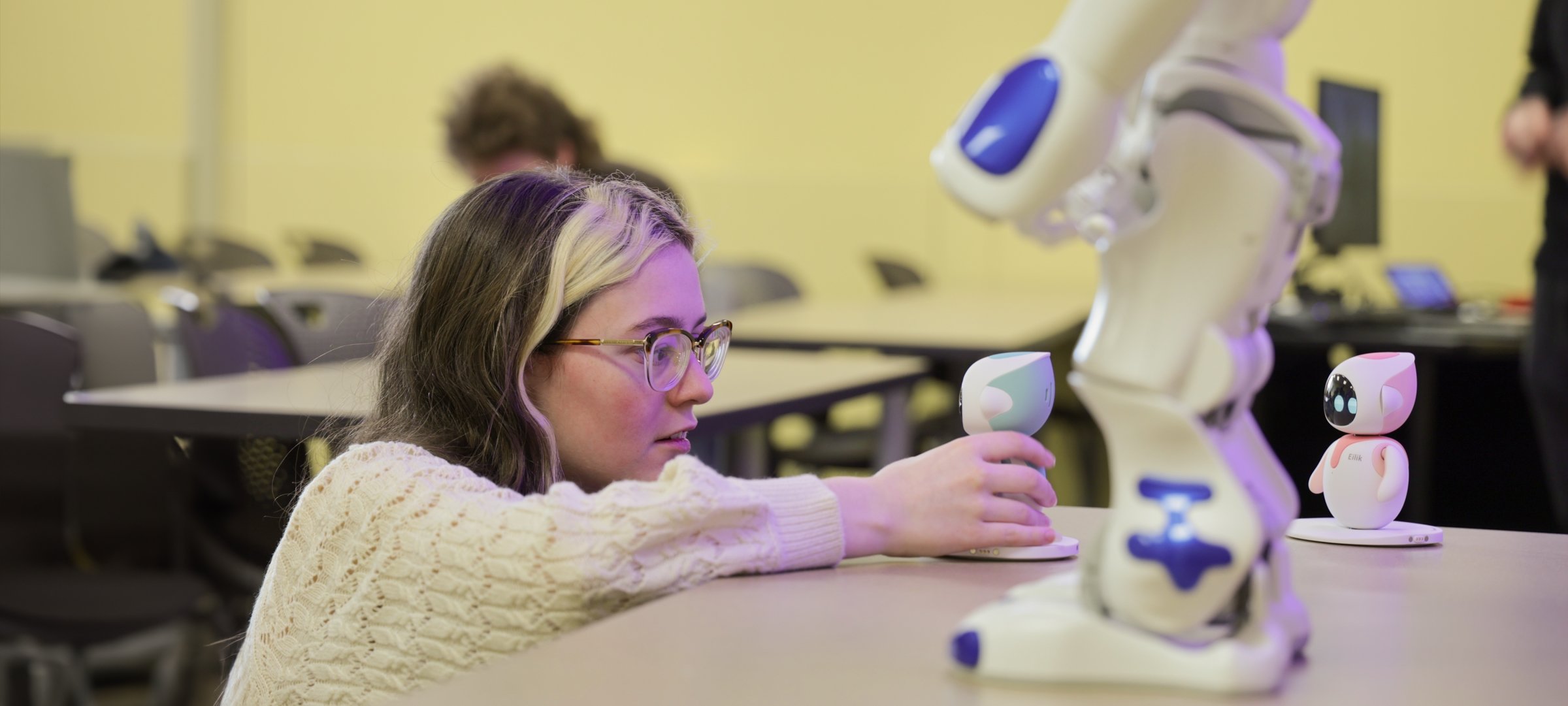 A student in Interpersonal Communication interacts with one of several social robots.