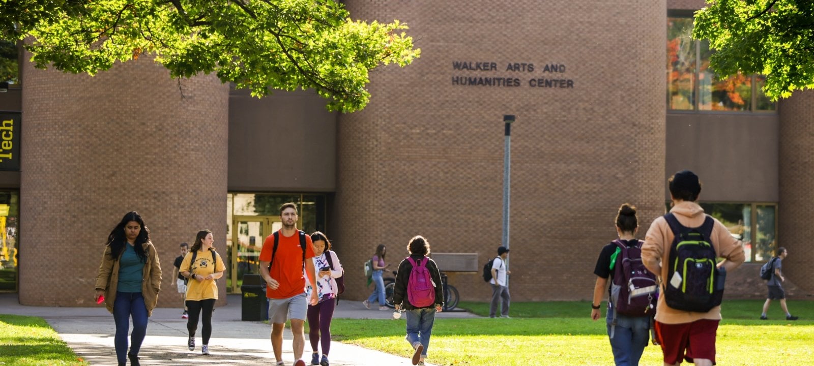 View of the front of Walker Arts & Humanities Center in bright sunlight with students walking to and from the building.