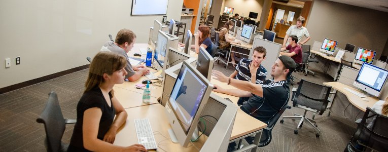 Students sitting at computers and some are interacting with each other for projects.