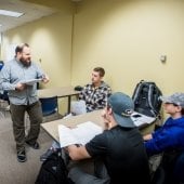 Faculty standing and talking to students in a group.