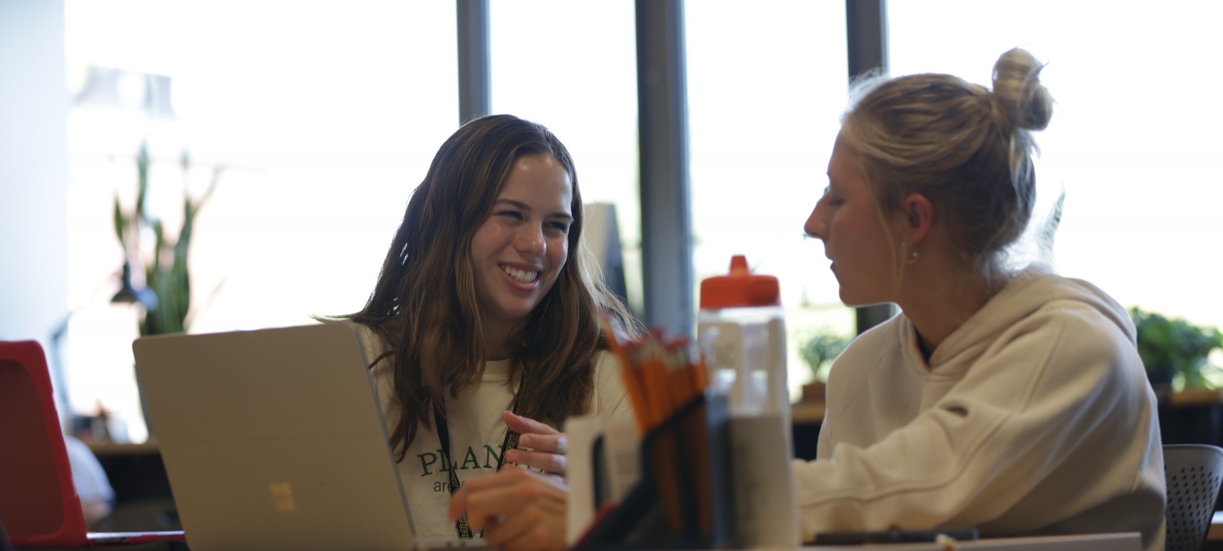 Two students discussing what they see on a laptop screen in front of them