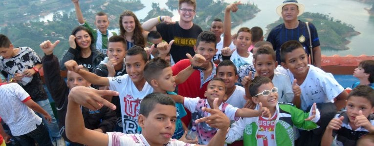 Michigan Tech student in Peru with a group of children posing for a photograph.