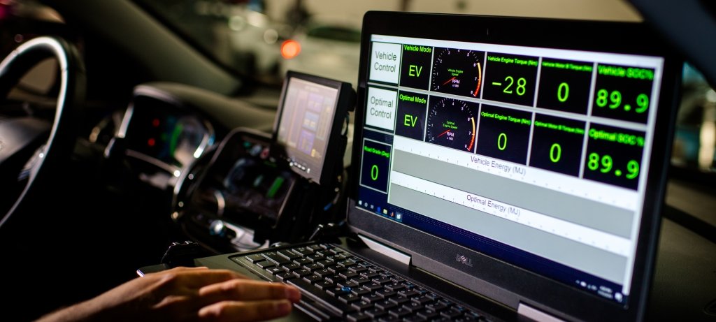 Researcher inside a vehicle with a laptop running diagnostics.