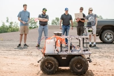Jeremy Bos and students outdoor with a remote operated vehicle