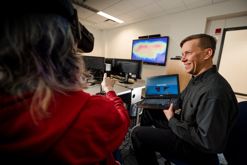 a studenty works on a VR headset as Dr. Vertanen holds a laptop