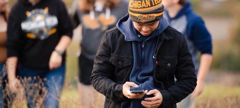 Man in MTU hat looks at cell phone