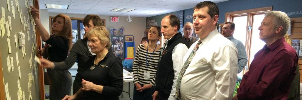 A group of people contemplating a board with post-it notes containing improvement