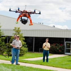 Two men operate a small drone.