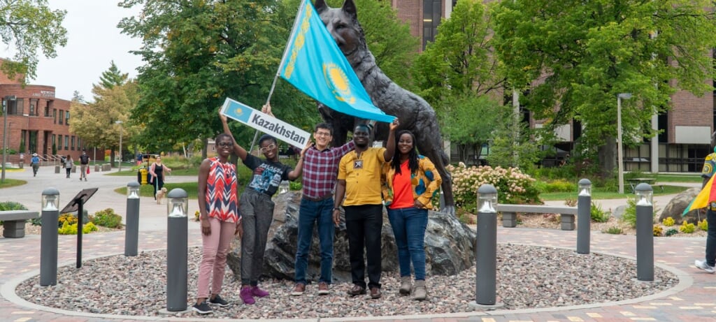 Photo of community holding flag outside in front of the husky statue