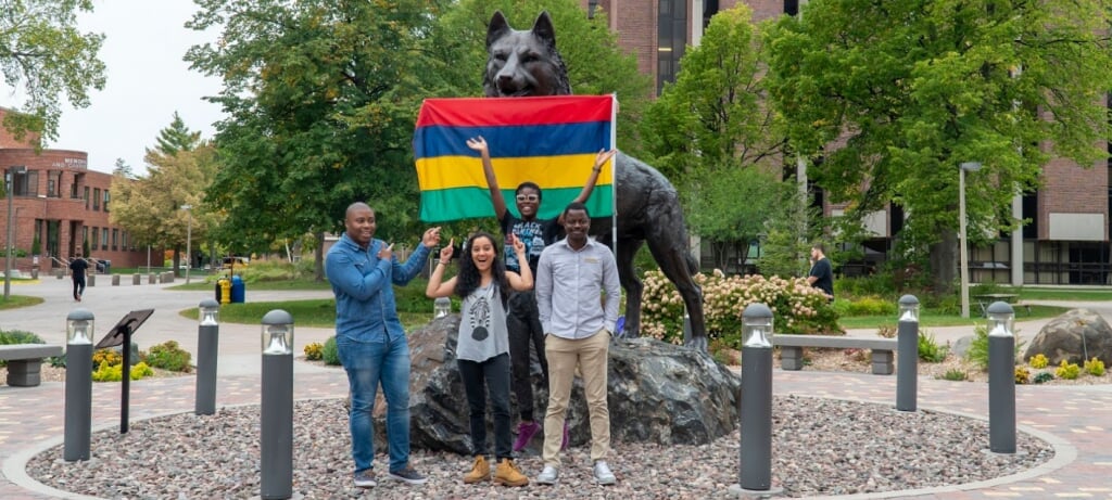 Community excitedly holds flag in front of the husky statue