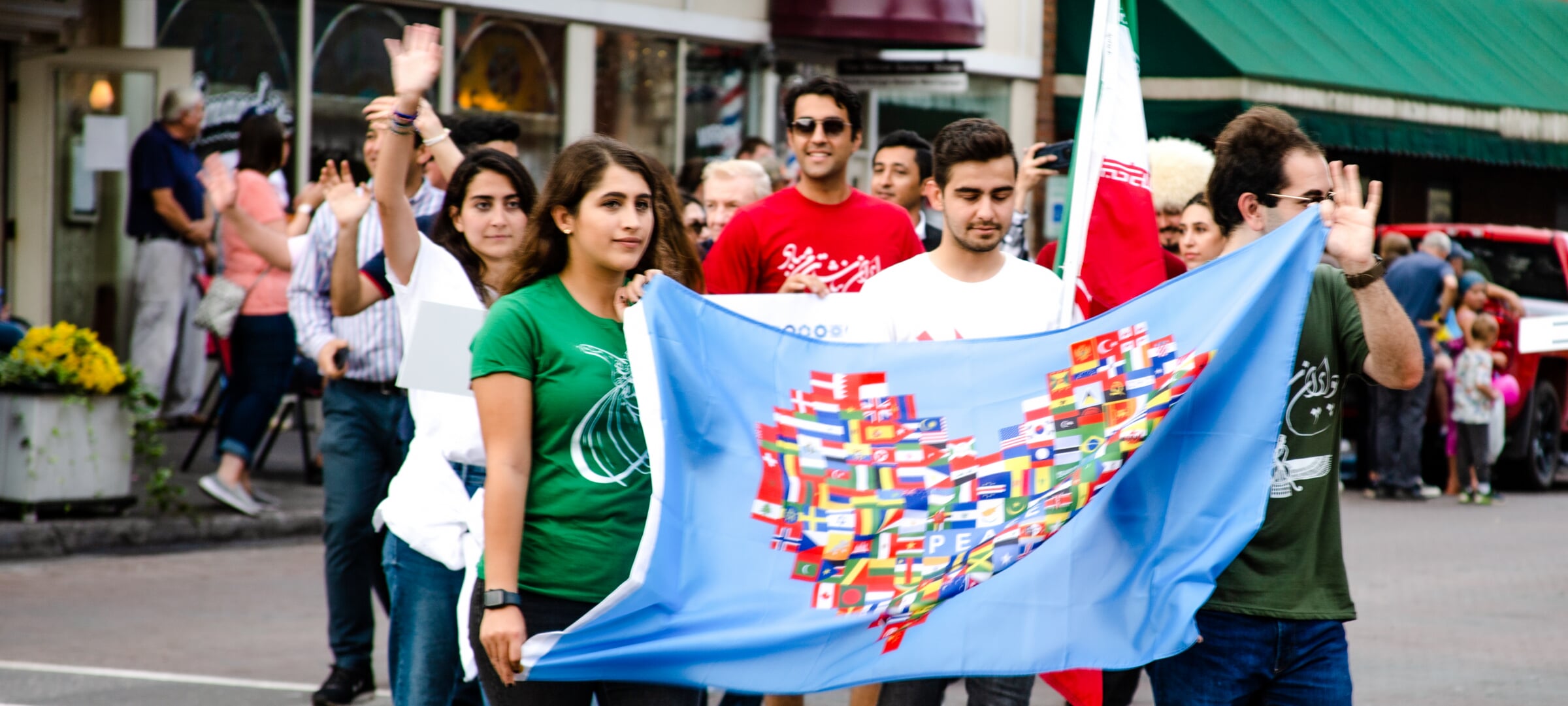 Students as the previously Parade of Nations holding a flag with heart made out of different countries flags