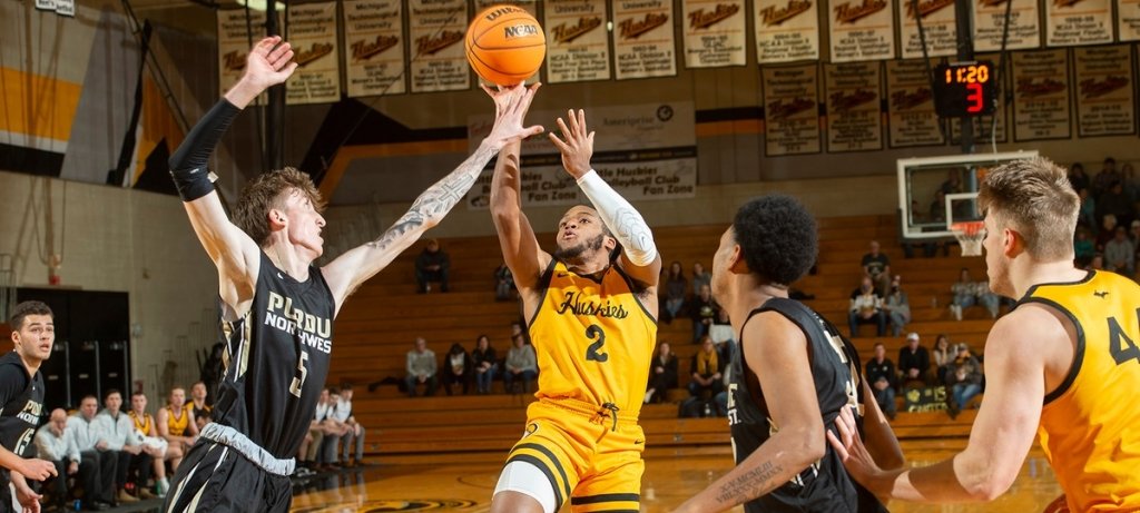 a huskies basketball player poised to shoot surrounded by other players