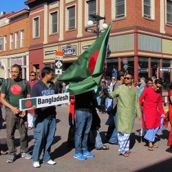 students representing Bangladesh carry a sign and flag in the parade of nations