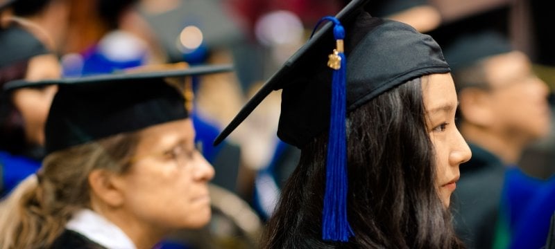 Two graduates at commencement watching