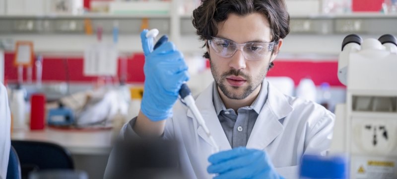 Researcher using automatic pipette in laboratory