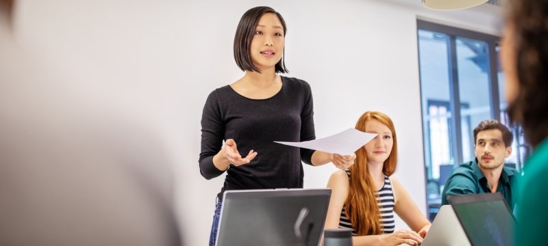 One student standing speaking at a conference table while others listen