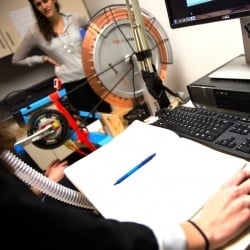 Female Researcher looking on as participant vitals are monitored while interacting with a computer