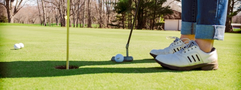 Upclose view of woman putting a golf ball into the hole at a golf course