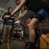 Participant on a exercise bik with breathing mask and researcher taking measurements