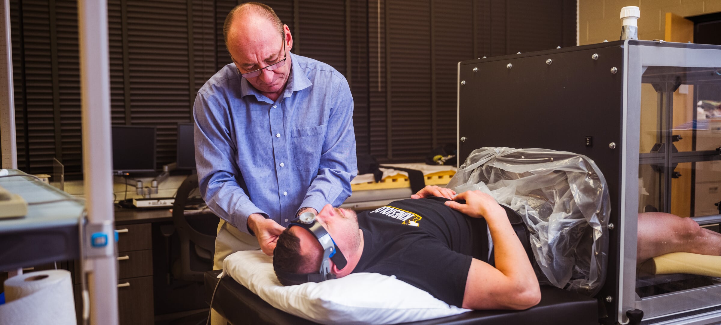 Faculty member adjusts headband brain activity monitor on student