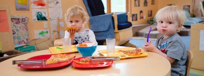 Two children eating at a table in the classroom.