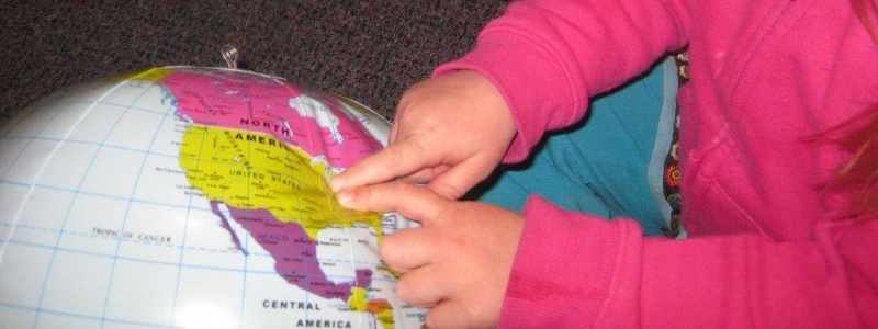 Child pointing to a location on a blow up globe.