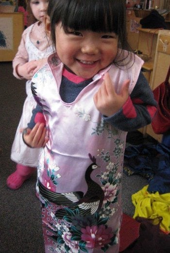 Girl playing dress up in a pink Chinese dress.