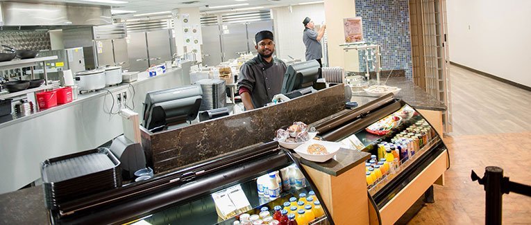 Student worker standing at the cash register behind the newly remodeled dining area in the Memorial Union.