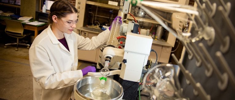 Female student operating equipment in the lab.