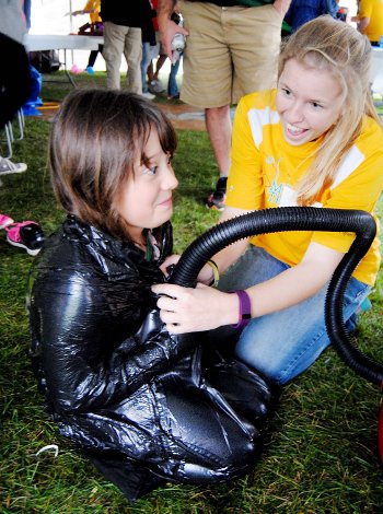 A participant is wrapped in a garbage bage while a Mind Trekker removes all of the air with a vacuum.