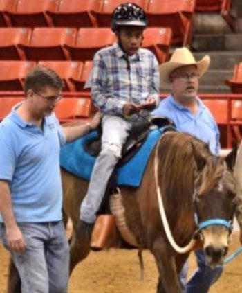 Draylon on a horse with two people walking next to him.