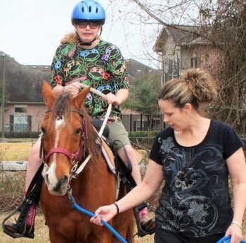 Gracie Gracie riding a horse with another person leading.