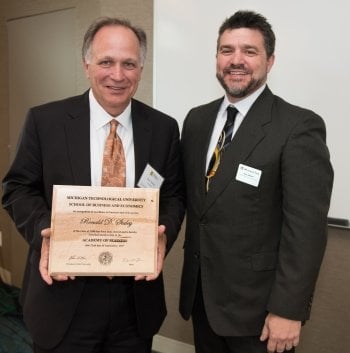 Ron Staley with a plaque standing next to Dean Johnson.