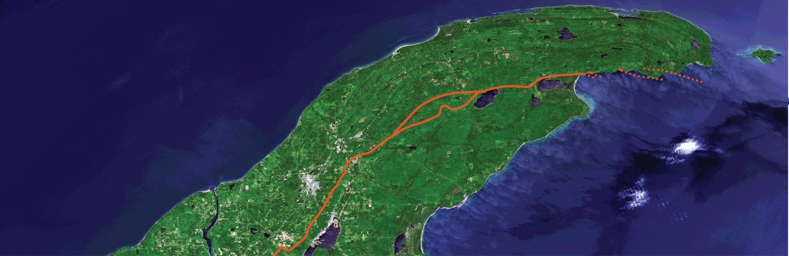 The orange line is the current interpretation of the Keweenaw Fault location. Based on Graff and Tyrrellâ€™s observations and analysis, the fault appears to be a system of splay faults (shown here by dotted lines) rather than a single thrust fault. This may indicate the termination of the fault at the eastern end of the Peninsula. Image Credit: Landsat satellite image of Keweenaw Peninsula provided by DigitalGlobe, a Maxar company.