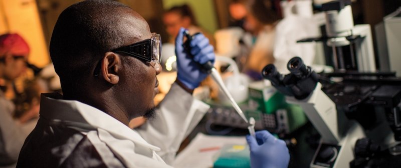Man in a lab near a microscope.