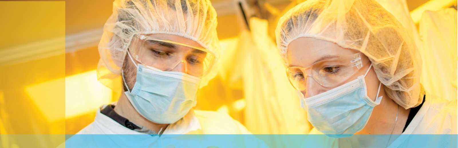 Two people with hair nets, masks, and safety glasses.